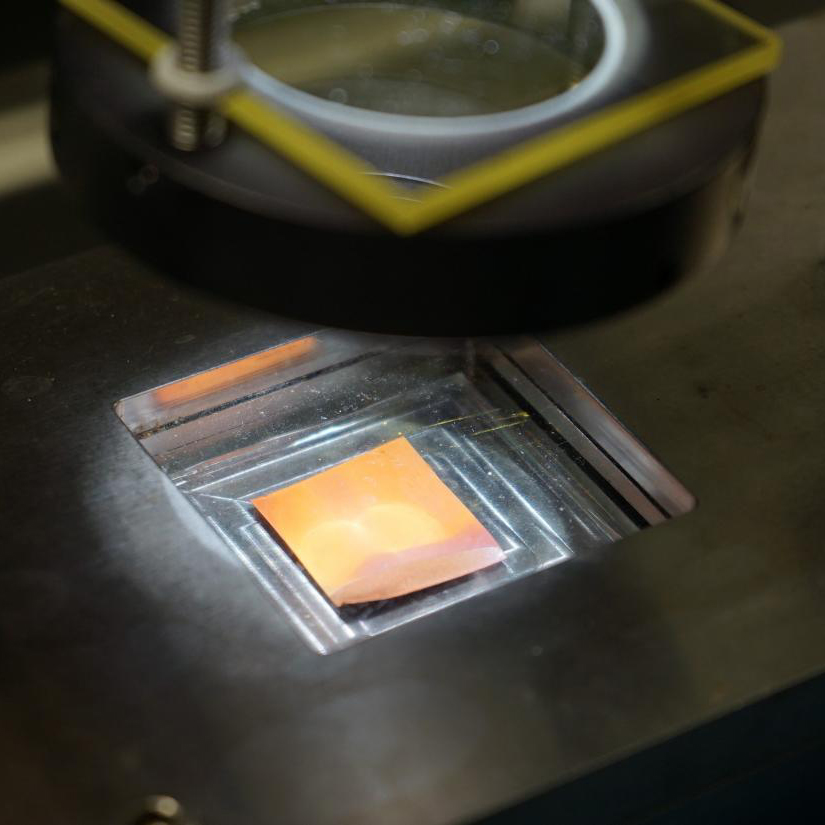 Close-up of a small copper-colored material under inspection, industrial and precise mood
